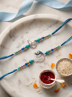 NVR Set of 2 Silver Toned Beaded Religious Thread Rakhi with Roli Chawal Chandan Mishri | Grocsy