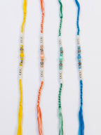 NVR Set of 4 Multicolor Artificial Beads Thread Rakhi with Roli Chawal Chandan Mishri | Grocsy