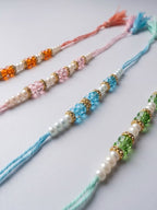 NVR Set of 4 White Pearls & Multicolor Thread Rakhi With Roli Chawal Chandan Mishri | Grocsy