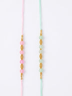 NVR Set of 2 Pink & Green Artificial Beads Thread Rakhi With Roli Chawal Chandan Mishri | Grocsy