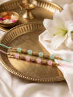 NVR Set of 2 Pink & Green Artificial Beads Thread Rakhi With Roli Chawal Chandan Mishri | Grocsy